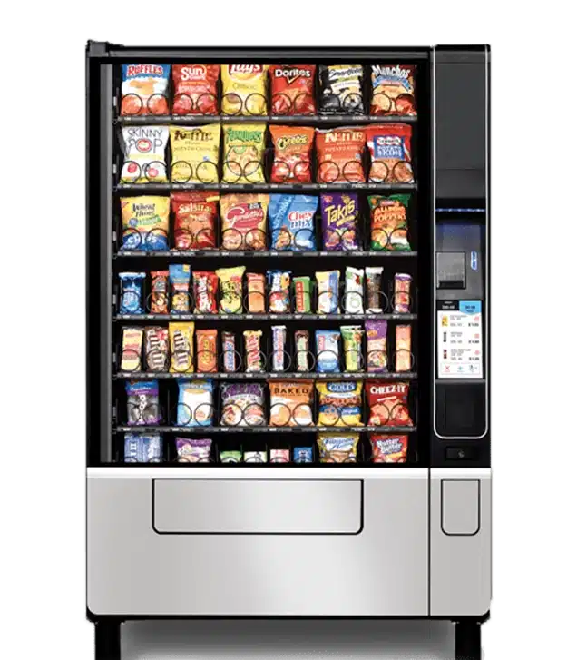 A vending machine filled with various snacks, including chips, cookies, crackers, candy bars, and other packaged treats, displayed in rows behind a glass front. Payment and selection panel is on the right side.